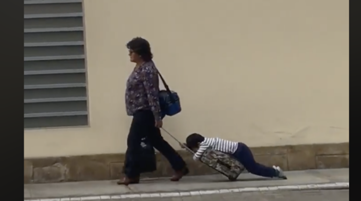 Madre arrastra a su hijo en su mochila con ruedas